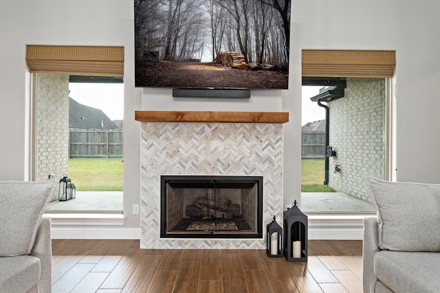 living room featuring a tile fireplace, wood-type flooring, and a wealth of natural light