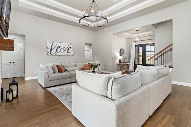 living room with french doors, dark wood-type flooring, an inviting chandelier, and a tray ceiling