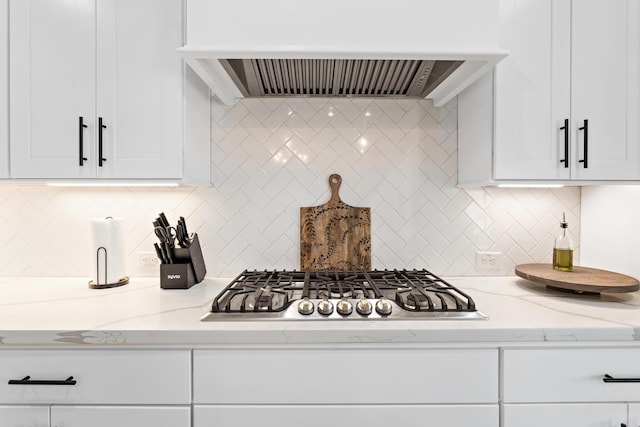 kitchen with light stone counters, white cabinets, and premium range hood