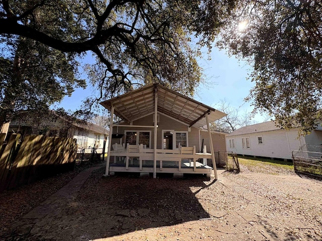 rear view of house featuring a deck and fence