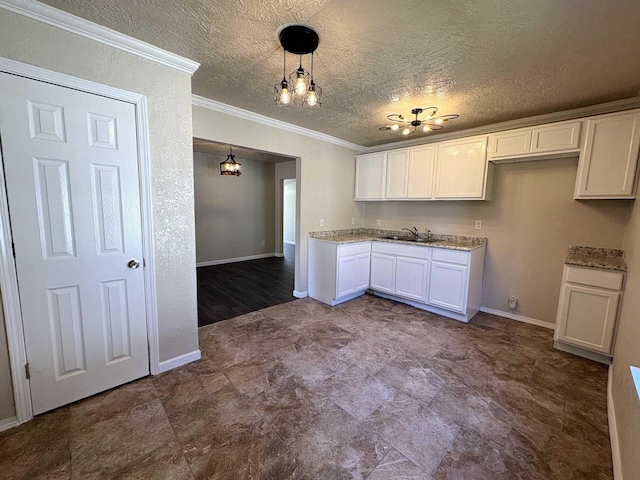 kitchen with white cabinets, light stone countertops, crown molding, and a sink