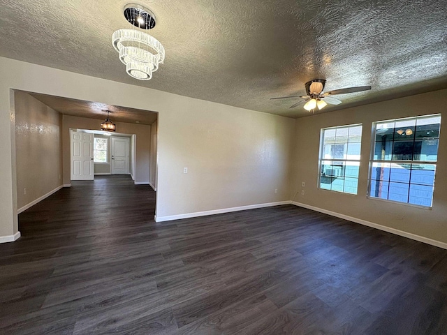 empty room featuring baseboards, a textured ceiling, dark wood finished floors, and ceiling fan with notable chandelier