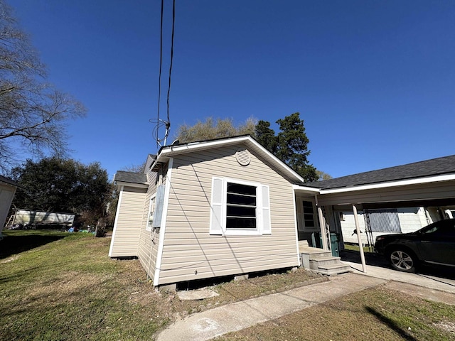 view of side of home featuring a carport and a lawn