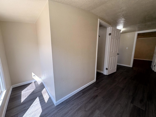 hallway featuring baseboards, a textured ceiling, and dark wood-style floors