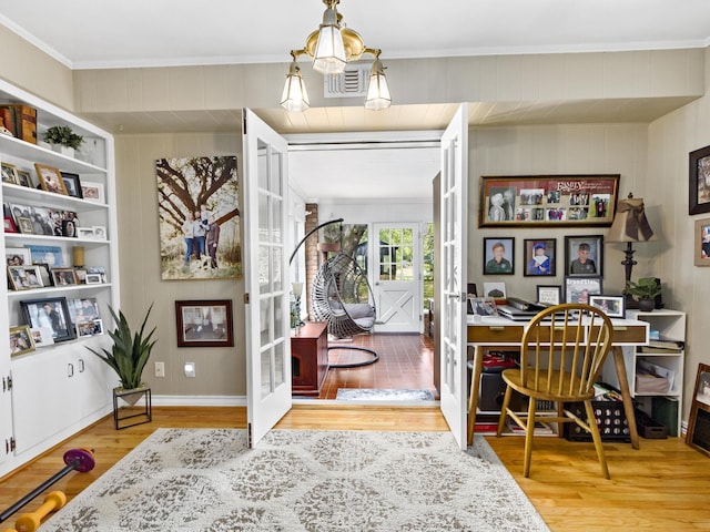 entryway with french doors, wood walls, ornamental molding, and wood-type flooring