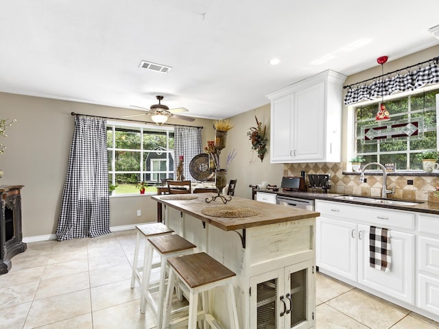 kitchen with white cabinets, backsplash, ceiling fan, and sink