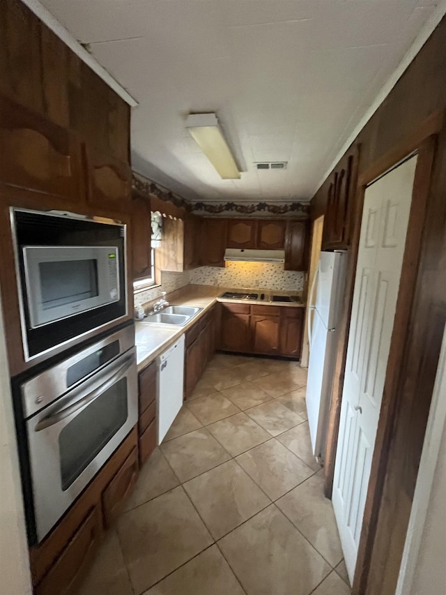 kitchen with light tile patterned floors, appliances with stainless steel finishes, sink, and backsplash