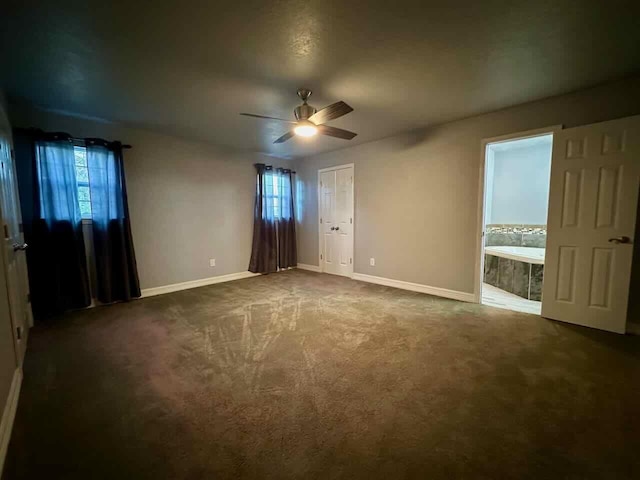 207 Lucky Dr, Silsbee, TX 77656 - unfurnished bedroom featuring baseboards, dark carpet, connected bathroom, and a ceiling fan