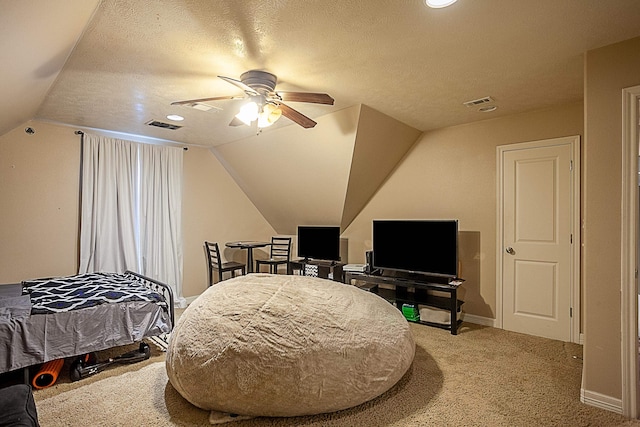 bedroom with ceiling fan, vaulted ceiling, carpet floors, and a textured ceiling