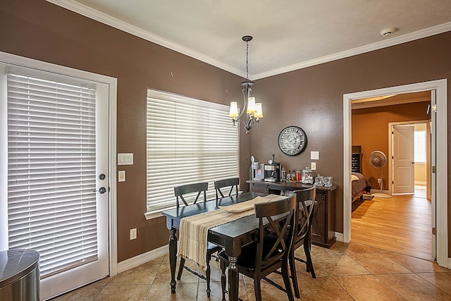 tiled dining room with a healthy amount of sunlight, ornamental molding, and an inviting chandelier