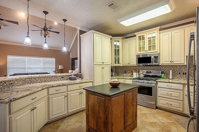 kitchen with appliances with stainless steel finishes, decorative light fixtures, ornamental molding, a kitchen island, and cream cabinets