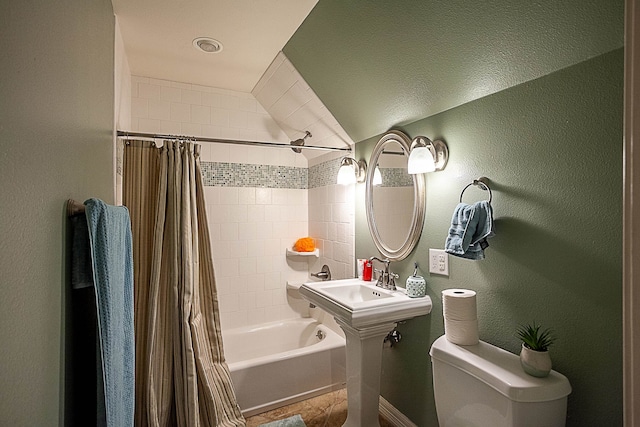 bathroom featuring a textured ceiling, toilet, lofted ceiling, and shower / tub combo