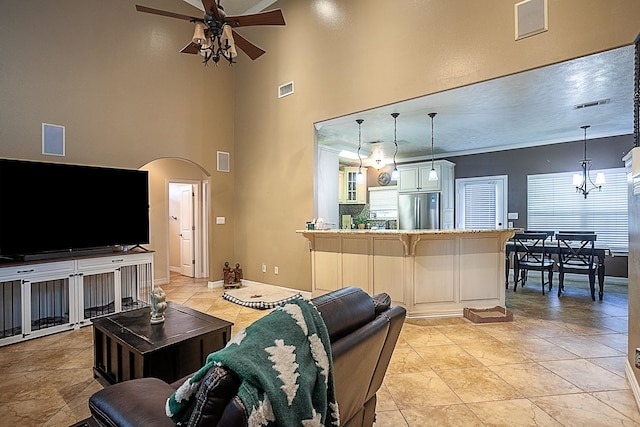 living room with ceiling fan with notable chandelier, light tile patterned floors, and a towering ceiling