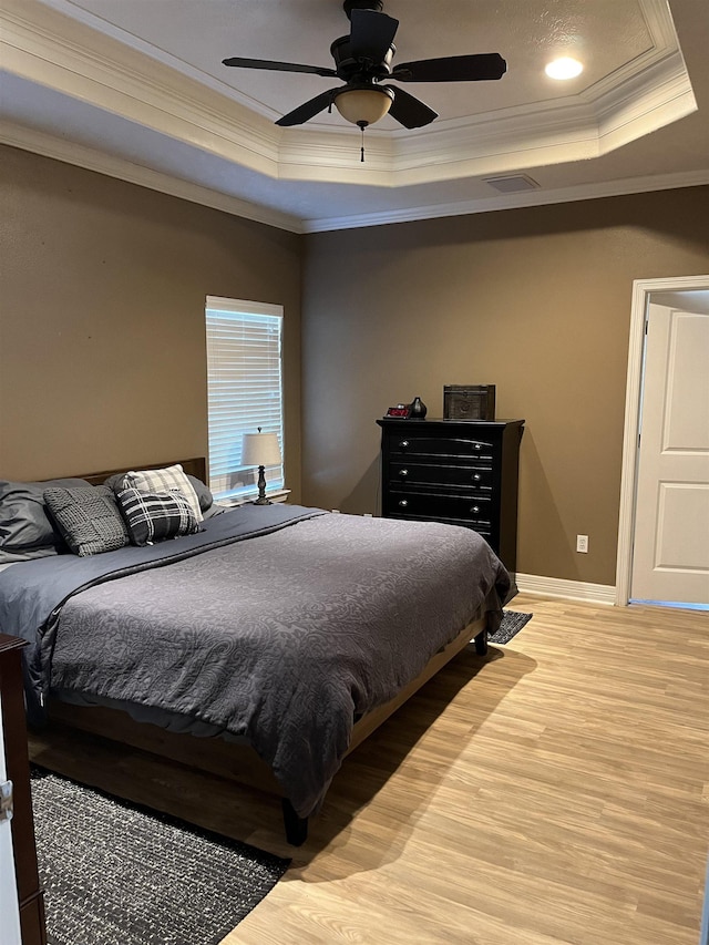 bedroom with ceiling fan, hardwood / wood-style floors, a tray ceiling, and crown molding