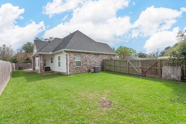 rear view of house featuring central AC and a lawn