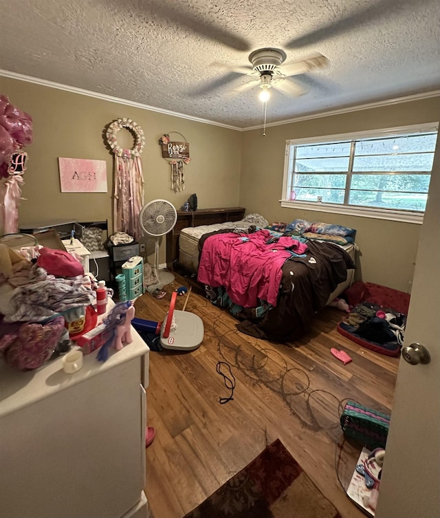 bedroom featuring a textured ceiling, ceiling fan, wood-type flooring, and ornamental molding