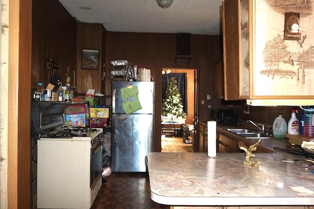 1720 Elgie St, Beaumont, TX 77705 - kitchen featuring freestanding refrigerator, white gas stove, wooden walls, dark floors, and stainless steel countertops