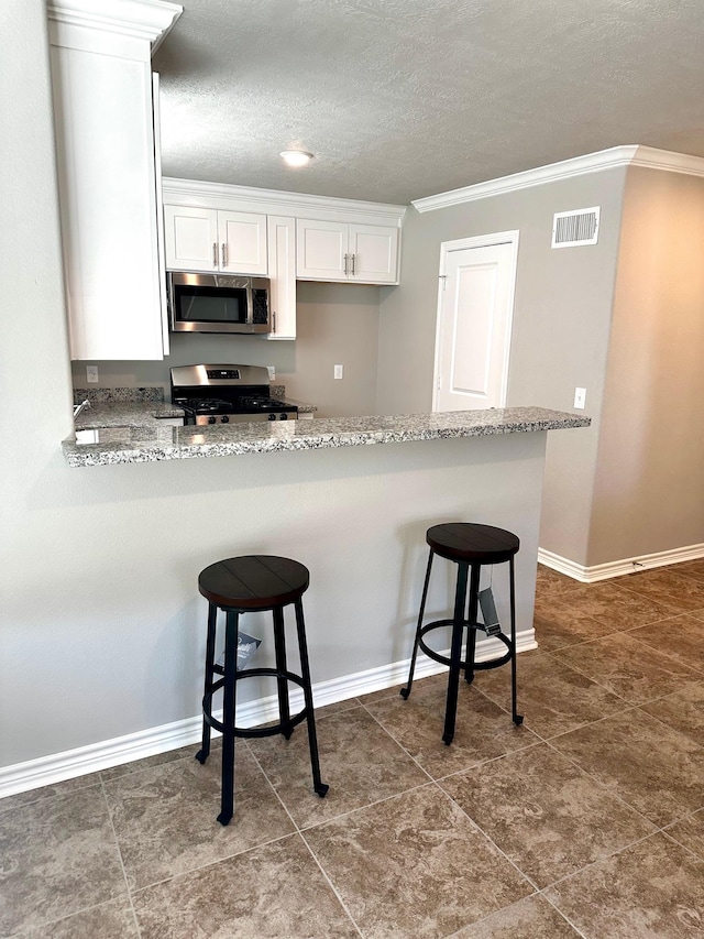 kitchen featuring light stone countertops, a breakfast bar, white cabinets, and stainless steel appliances