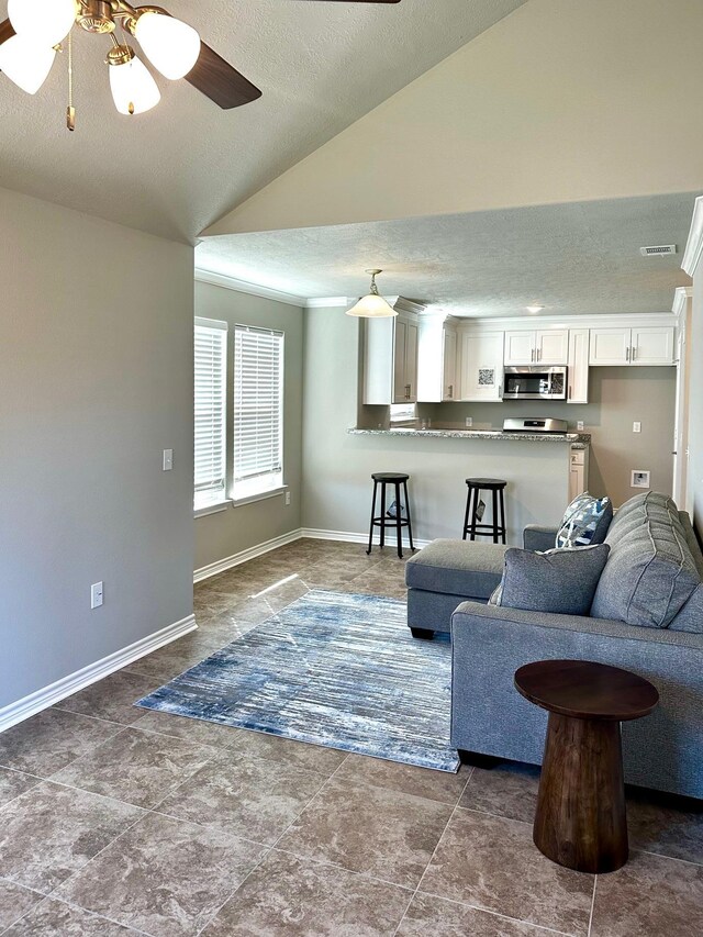 living room featuring a textured ceiling, ceiling fan, and lofted ceiling