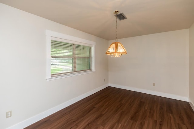 unfurnished room featuring baseboards, visible vents, an inviting chandelier, and dark wood-style floors
