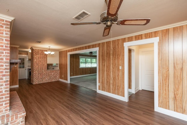 unfurnished living room featuring dark wood-style flooring, visible vents, baseboards, ornamental molding, and ceiling fan with notable chandelier