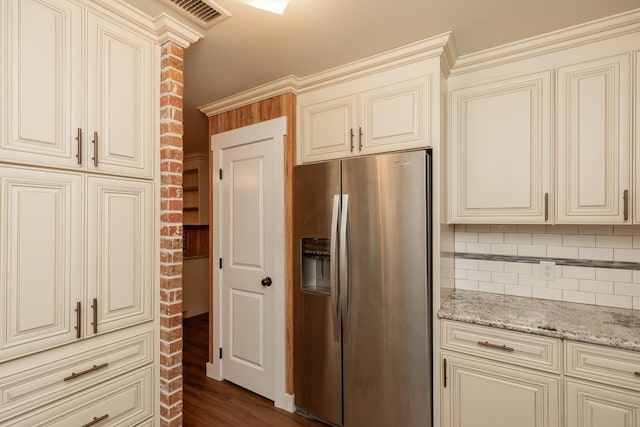 kitchen featuring light stone countertops, decorative backsplash, cream cabinetry, visible vents, and stainless steel fridge with ice dispenser