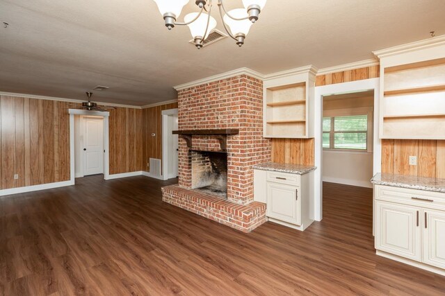 unfurnished living room featuring visible vents, baseboards, dark wood-style flooring, a fireplace, and a notable chandelier