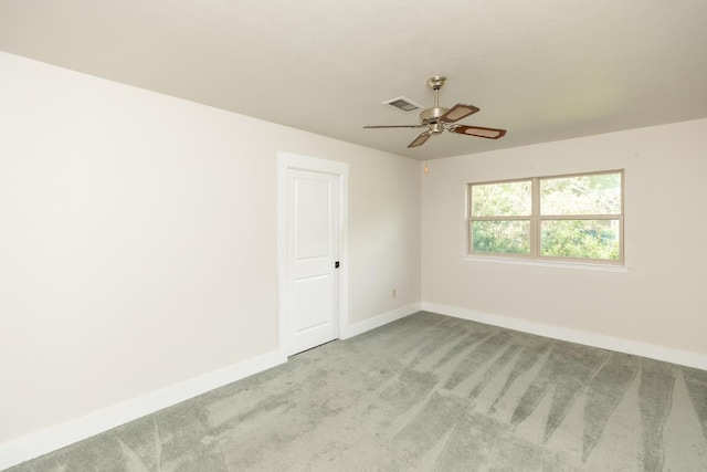 carpeted spare room with baseboards, visible vents, and a ceiling fan