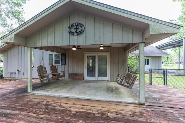 back of property with a deck, fence, board and batten siding, and a ceiling fan