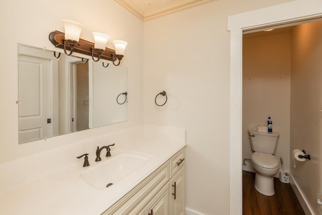 half bathroom with wood finished floors, toilet, vanity, baseboards, and crown molding