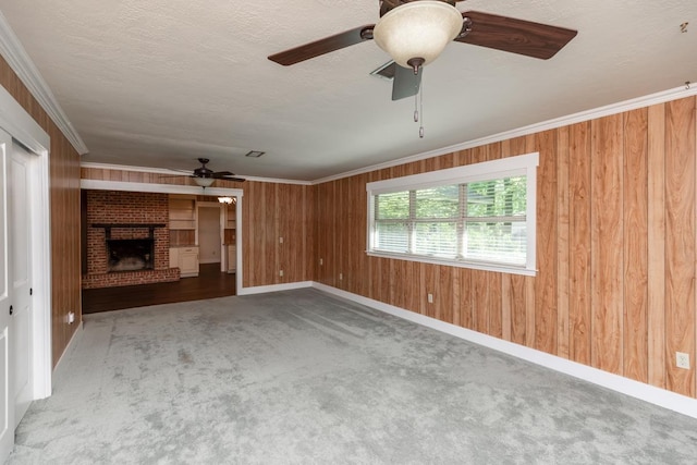 unfurnished living room with carpet floors, a brick fireplace, baseboards, a ceiling fan, and wooden walls