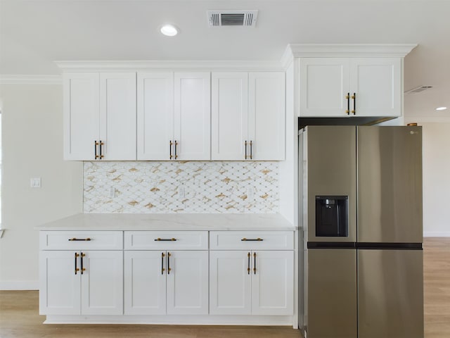 kitchen featuring stainless steel refrigerator with ice dispenser, tasteful backsplash, and white cabinets