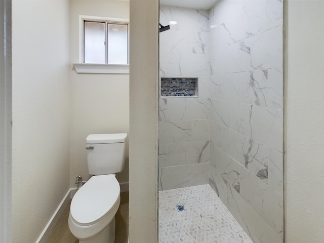 bathroom with a tile shower and toilet