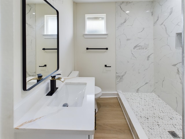 bathroom featuring plenty of natural light, tiled shower, hardwood / wood-style floors, and toilet