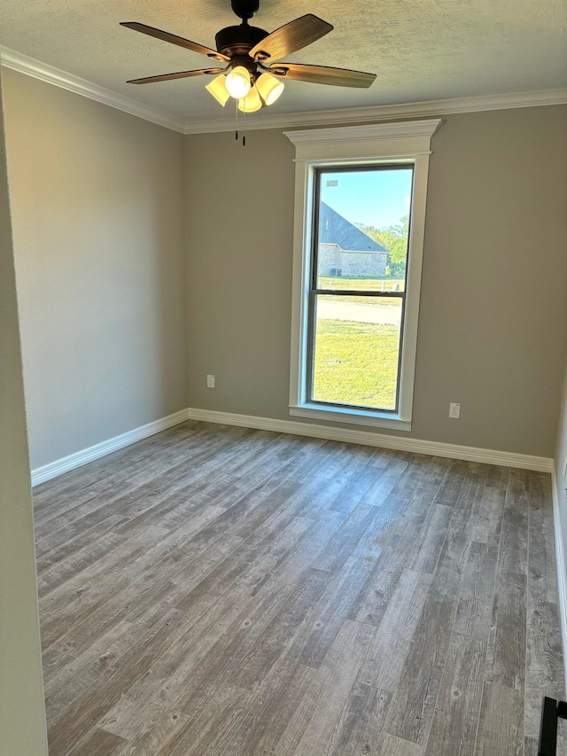 unfurnished room featuring hardwood / wood-style flooring, ceiling fan, a healthy amount of sunlight, and ornamental molding