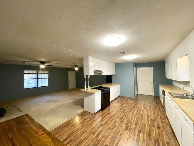 kitchen featuring black stove, light wood-type flooring, a textured ceiling, sink, and white cabinets