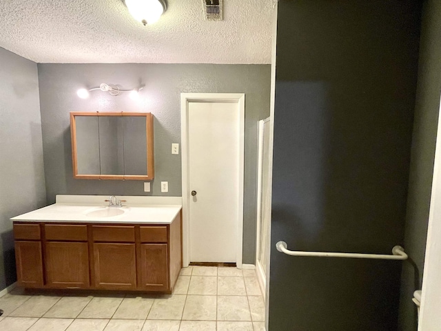 bathroom with tile patterned flooring, vanity, a shower with door, and a textured ceiling