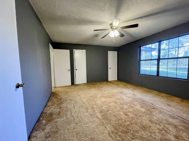 unfurnished bedroom with carpet flooring, ceiling fan, and a textured ceiling