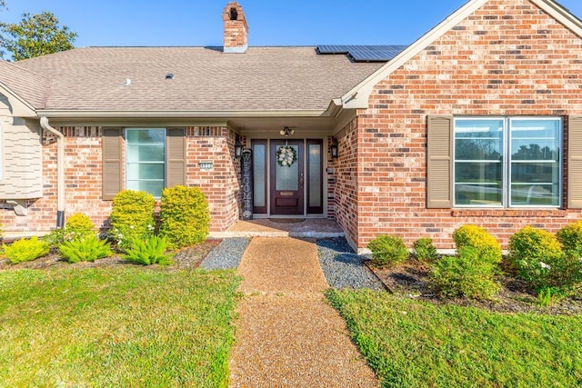 4910 Gladys Ave, Beaumont, TX 77706 - property entrance with brick siding, a shingled roof, a chimney, and solar panels