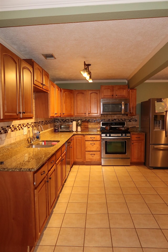 kitchen with sink, stainless steel appliances, light stone counters, a textured ceiling, and light tile patterned floors