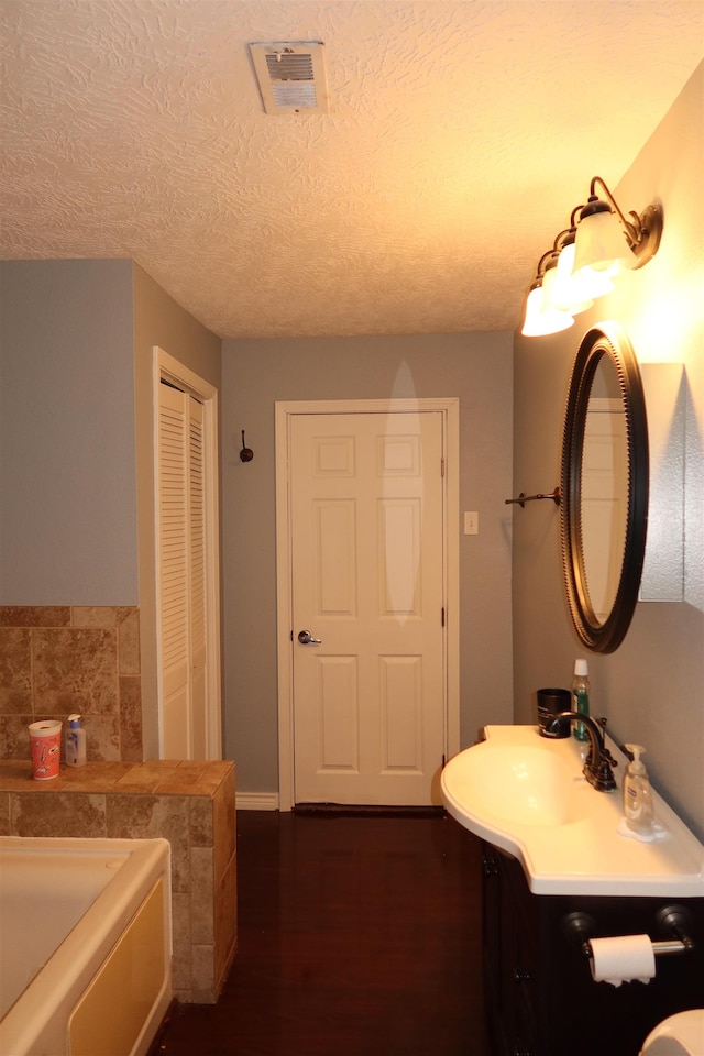 bathroom featuring a washtub, vanity, a textured ceiling, and hardwood / wood-style flooring