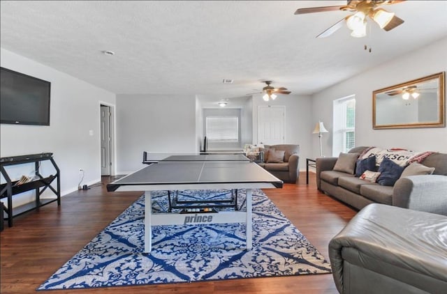 recreation room featuring dark wood-style flooring, visible vents, a textured ceiling, and baseboards