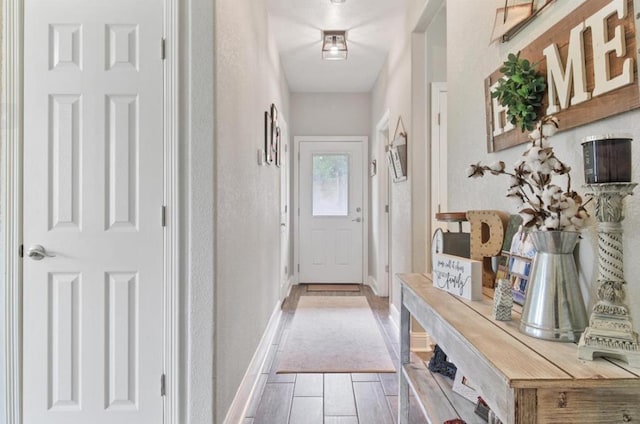 doorway featuring baseboards and light wood finished floors