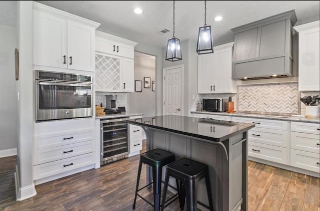 kitchen featuring beverage cooler, visible vents, a kitchen breakfast bar, custom exhaust hood, and stainless steel appliances