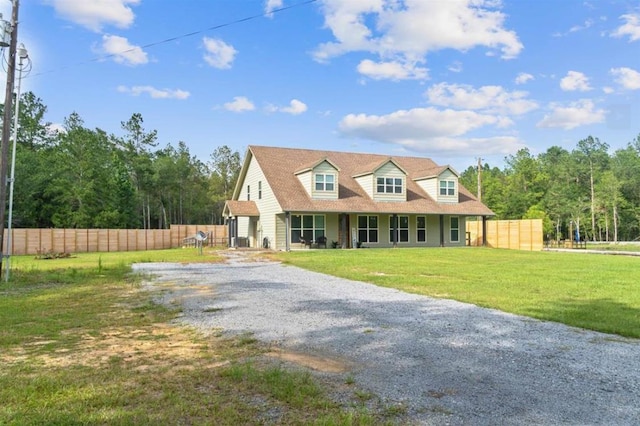 cape cod house with a front yard, fence, and gravel driveway