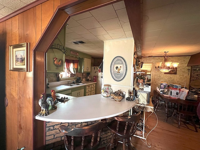 dining space with wood walls, wood finished floors, and a chandelier