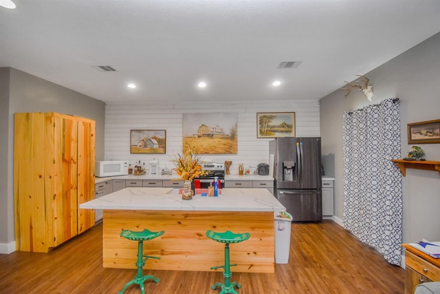 2000 Aggie Dr, Beaumont, TX 77713 - kitchen with appliances with stainless steel finishes, light wood finished floors, a center island, and light stone counters
