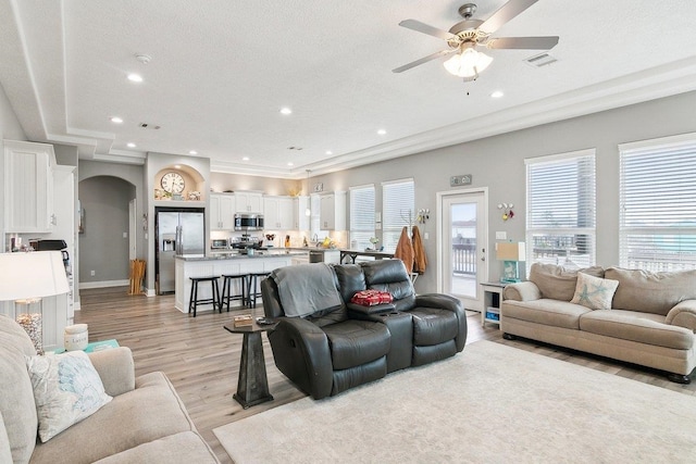 living room with ceiling fan, a textured ceiling, and light hardwood / wood-style flooring