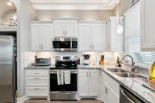 kitchen featuring appliances with stainless steel finishes, decorative light fixtures, sink, and white cabinets