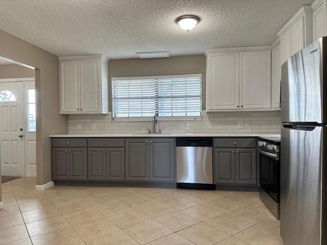 kitchen with sink, white cabinetry, stainless steel appliances, and light tile patterned floors